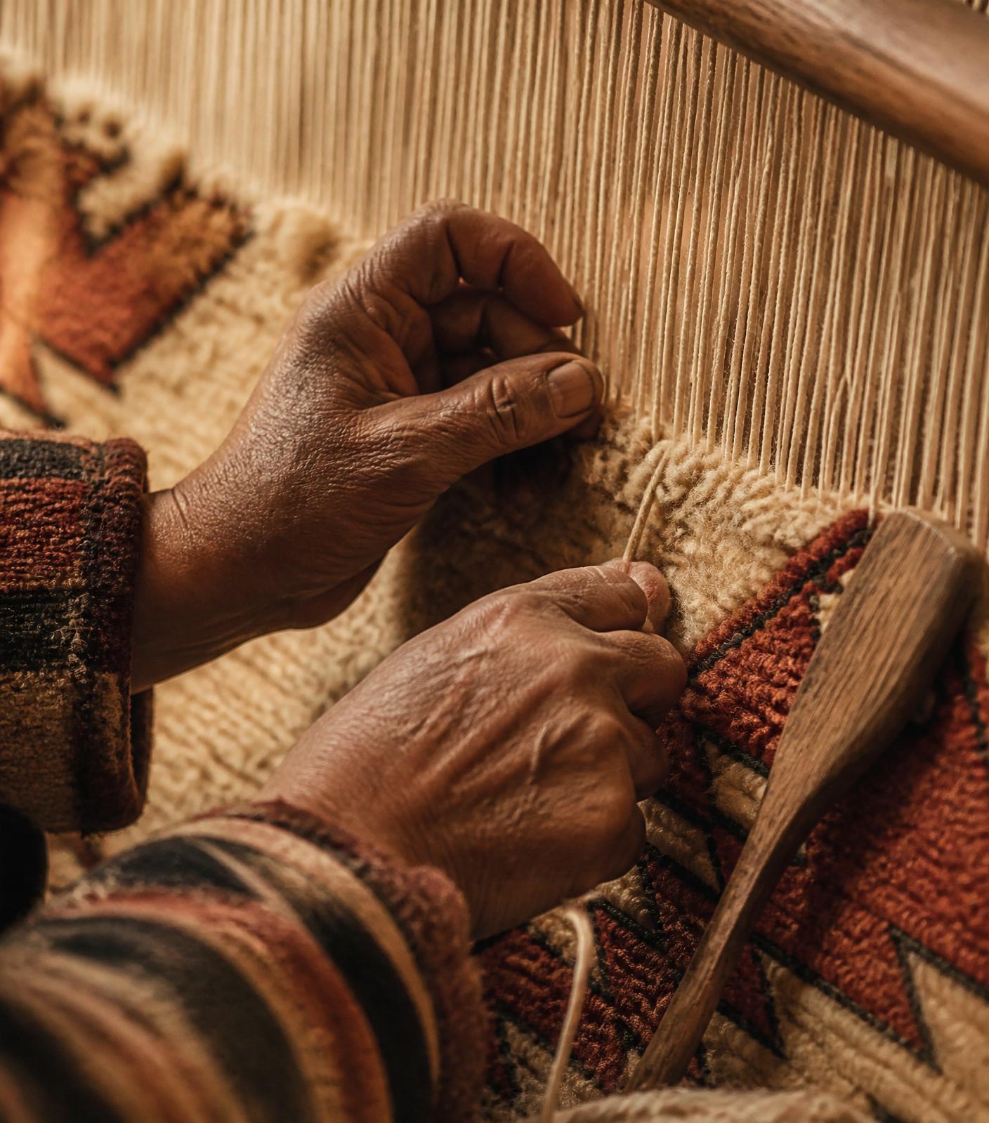 Berber artisan hands weaving wool on a traditional loom